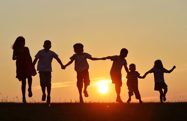 Happy children silhouettes on summer meadow running and jumping